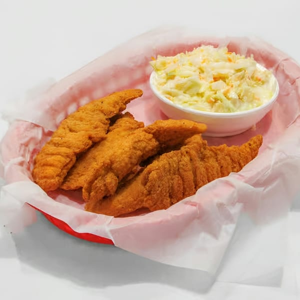 Fried chicken tenders and a side of coleslaw in a red basket lined with white paper.