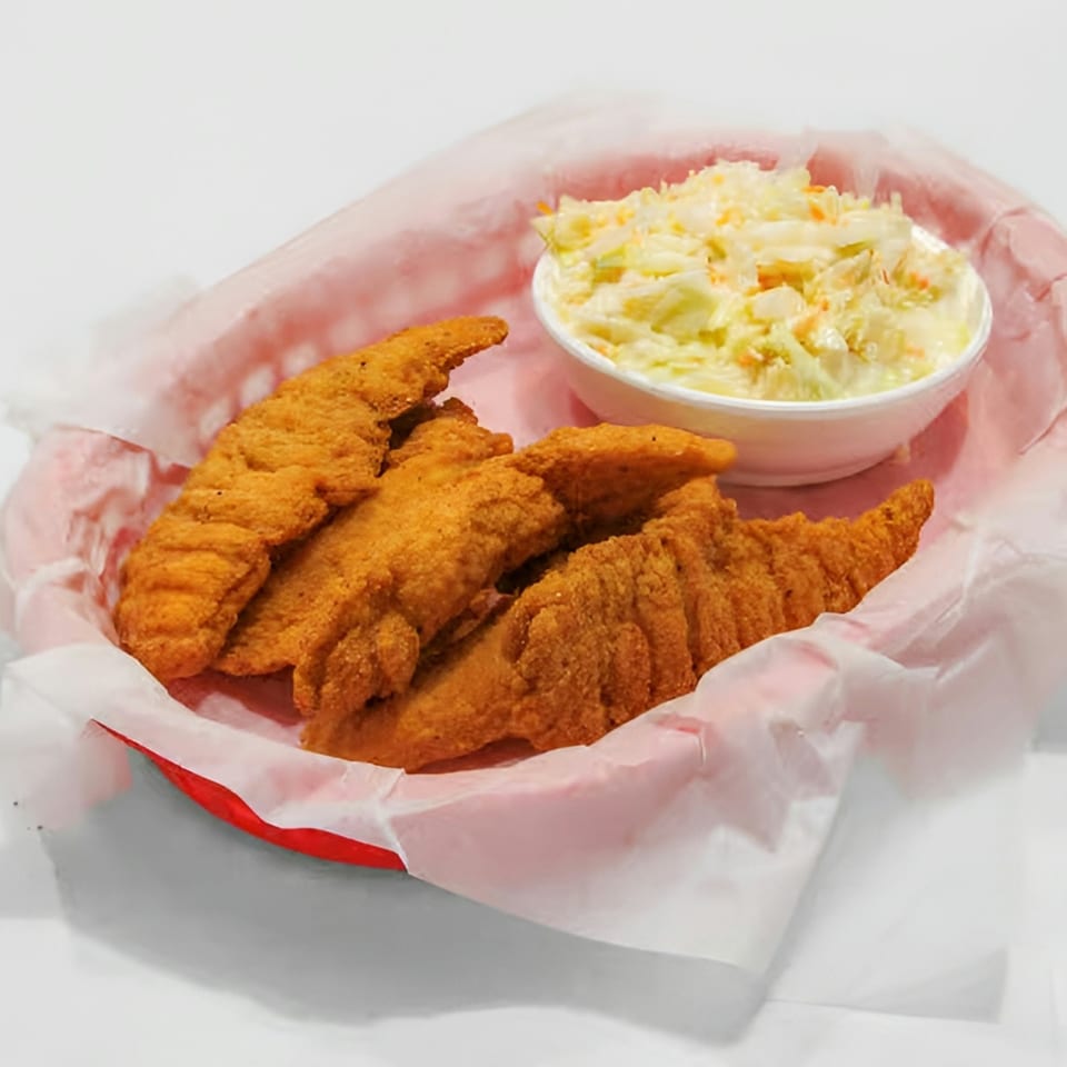 Fried chicken tenders and a side of coleslaw in a red basket lined with white paper.