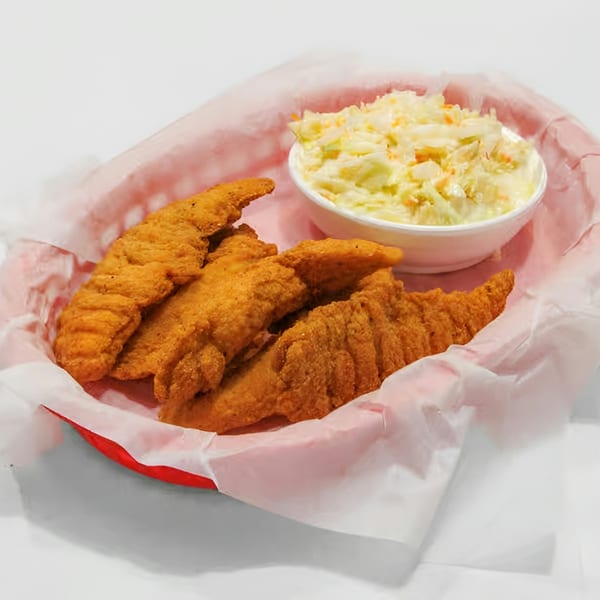 Crispy fried fish fillets and a side of creamy coleslaw in a red basket with white paper.