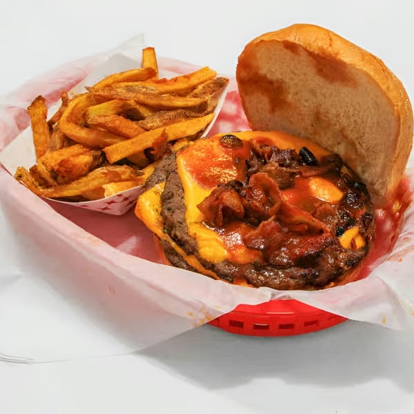 A double cheeseburger with bacon and barbecue sauce, served with a side of fries in-house fries.